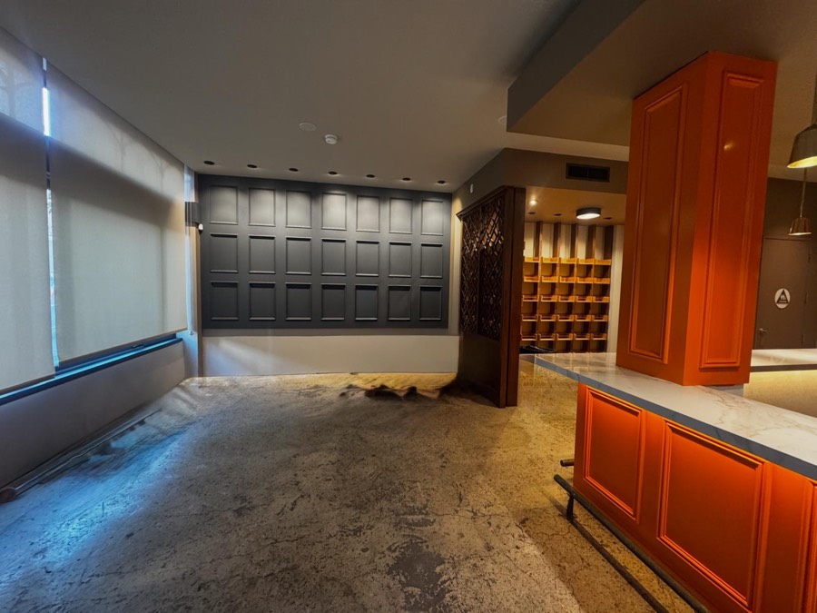 The new orange bar with a white marble top under brass pendant lights, with a ladder and supplies still on the floor