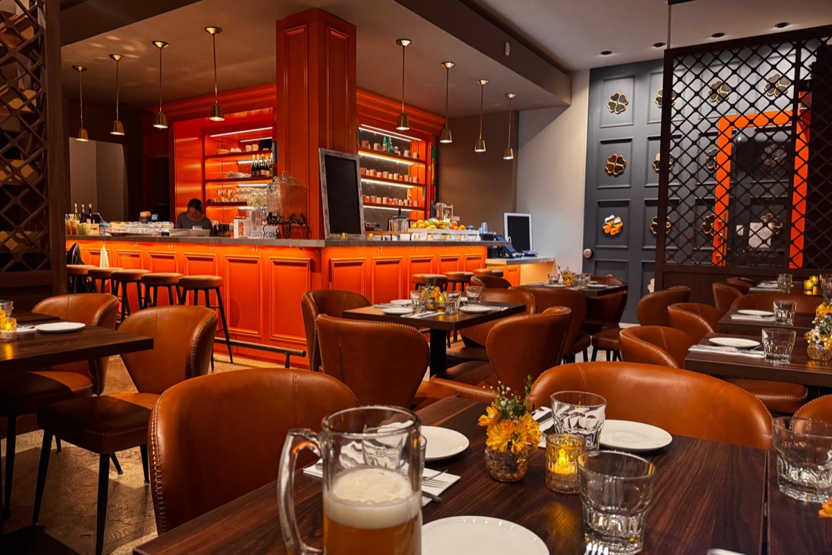 Wanjai's dining room: brown leather chairs, small yellow flowers and candles on the tables, and the orange bar under brass lights