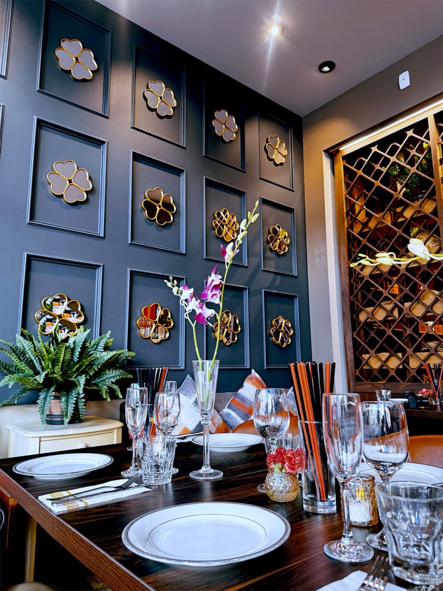 Place settings and orchids in front of the gray wall with golden clover mirrors