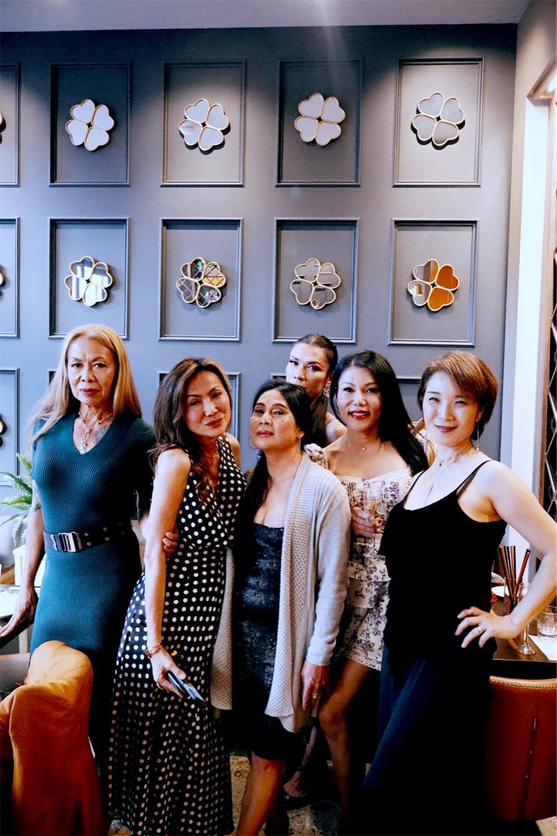 A group of friends posing together in front of the clover wall