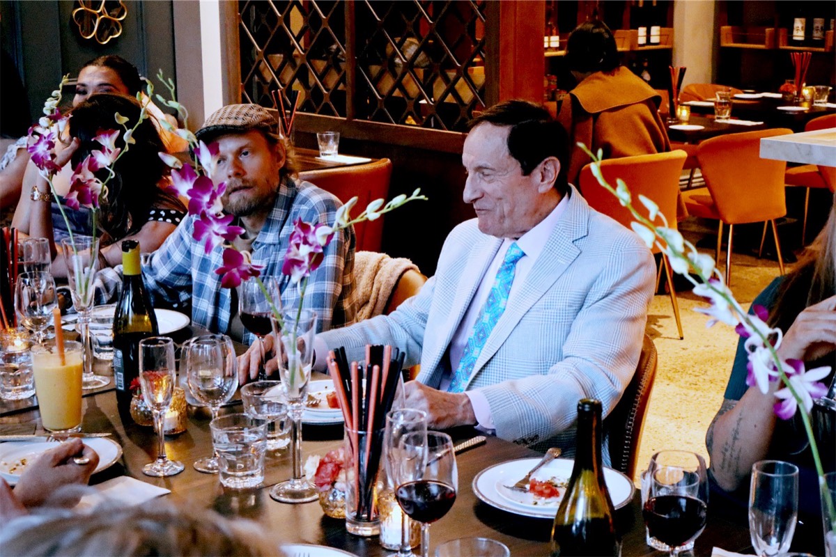 Guests laughing at the table among orchids and wine bottles