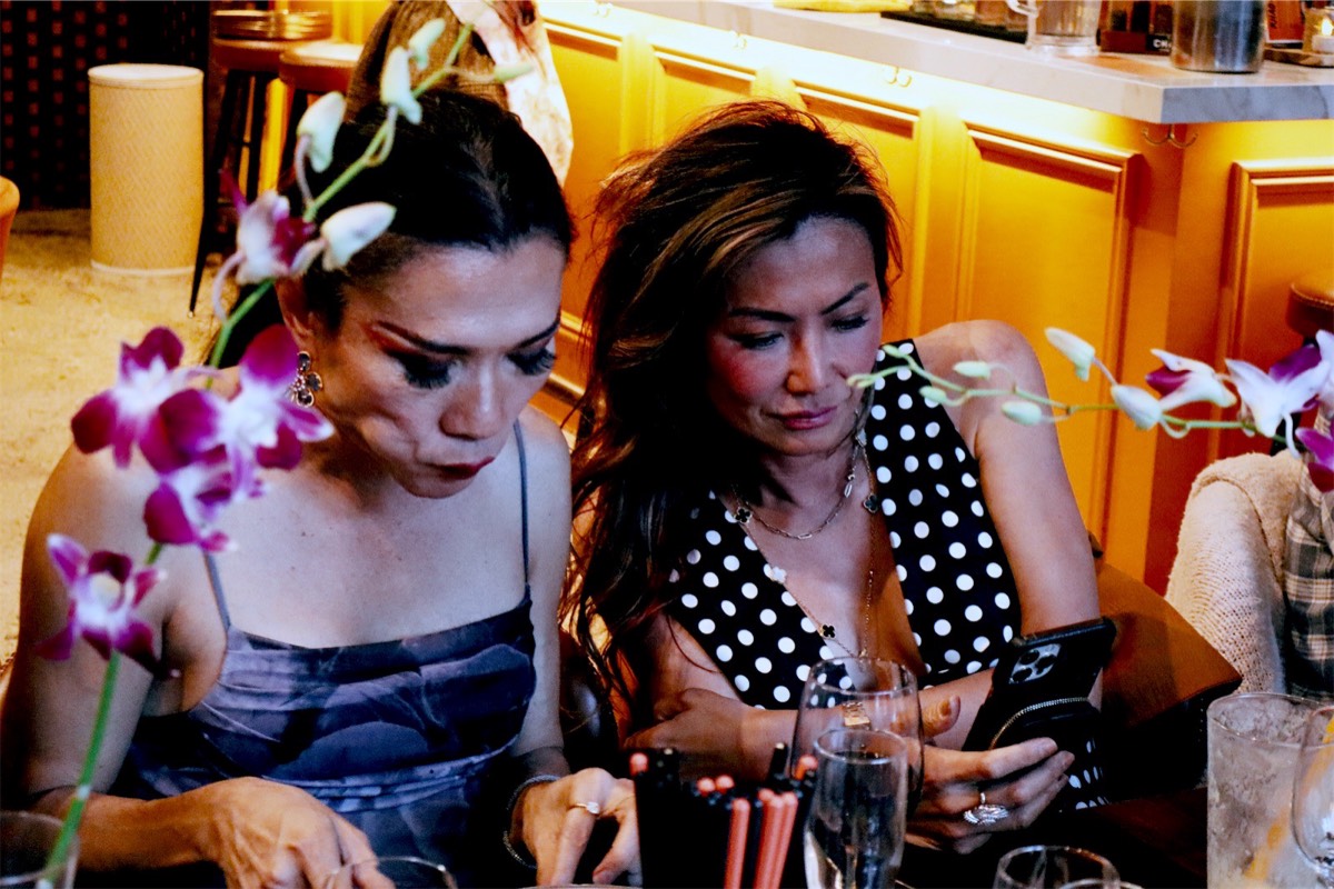 Two guests looking at a phone together at the table
