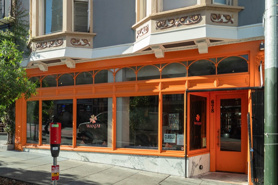 Wanjai's orange storefront on Geary Street, with arched windows, the clover logo on the glass, and the door at number 678