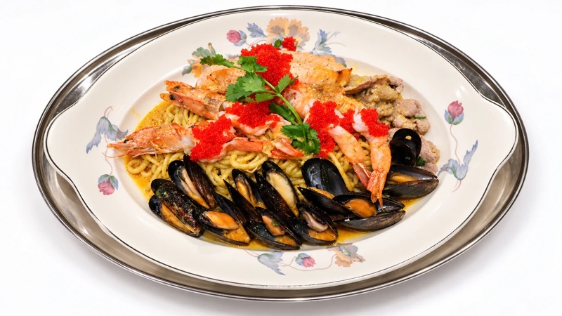 Seafood noodles on a painted oval platter, piled with prawns, salmon, mussels and orange roe